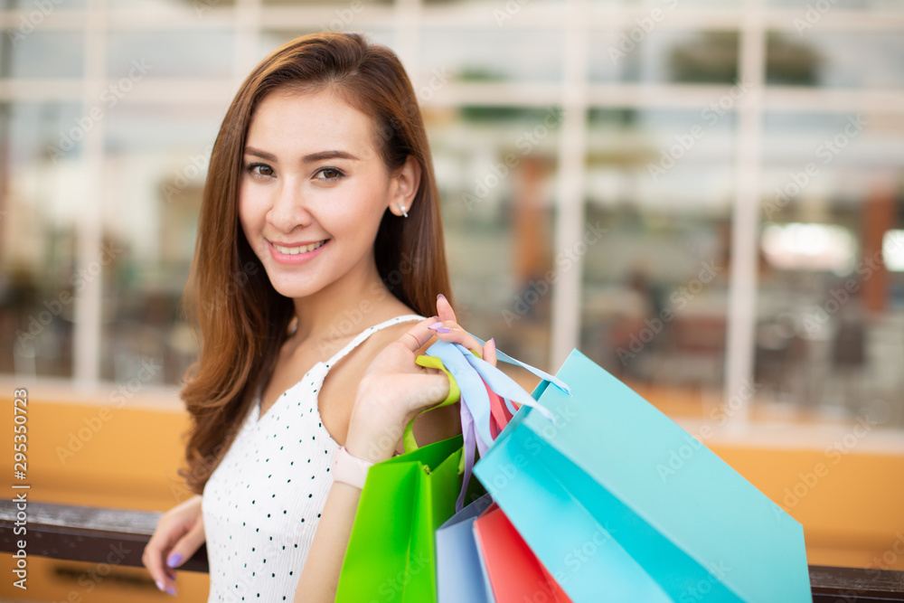 happiness, consumerism, sale and people concept - smiling young woman with shopping bags in shopping mall happiness, consumerism, sale and people concept - smiling young woman with shopping bags in shopping mall