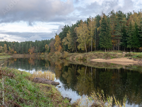 autumn landscape with river, calm water, beautiful colorful trees, water reflections, river Gauja, Valmiera, Latvia