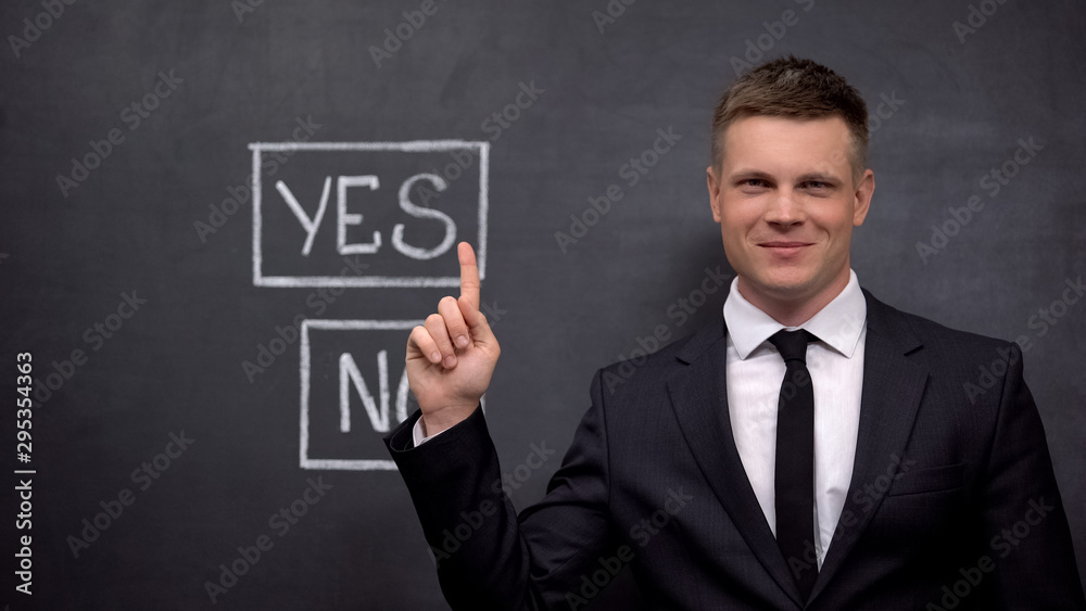 Smiling businessman showing yes button painted on blackboard, investment Smiling businessman showing yes button painted on blackboard, investment