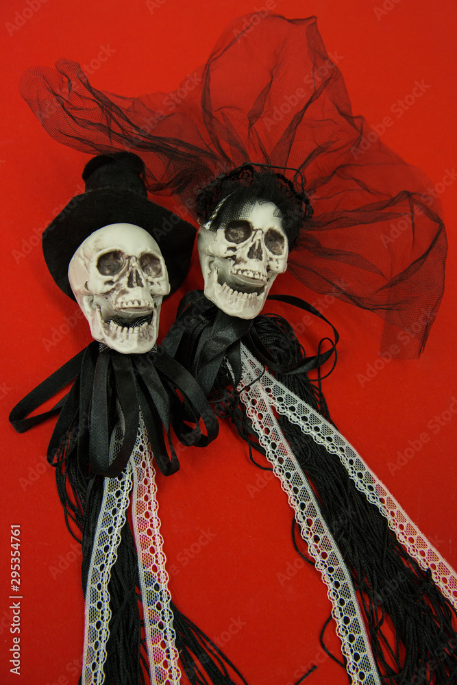 Fototapeta premium Bride and groom skull wedding dresses symbol of the day of the dead and hallowed, typical american party, with red background