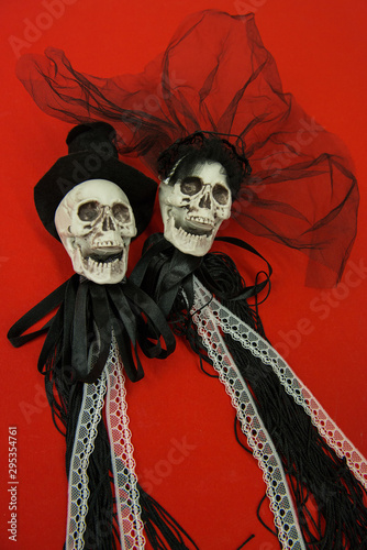 Bride and groom skull wedding dresses symbol of the day of the dead and hallowed, typical american party, with red background