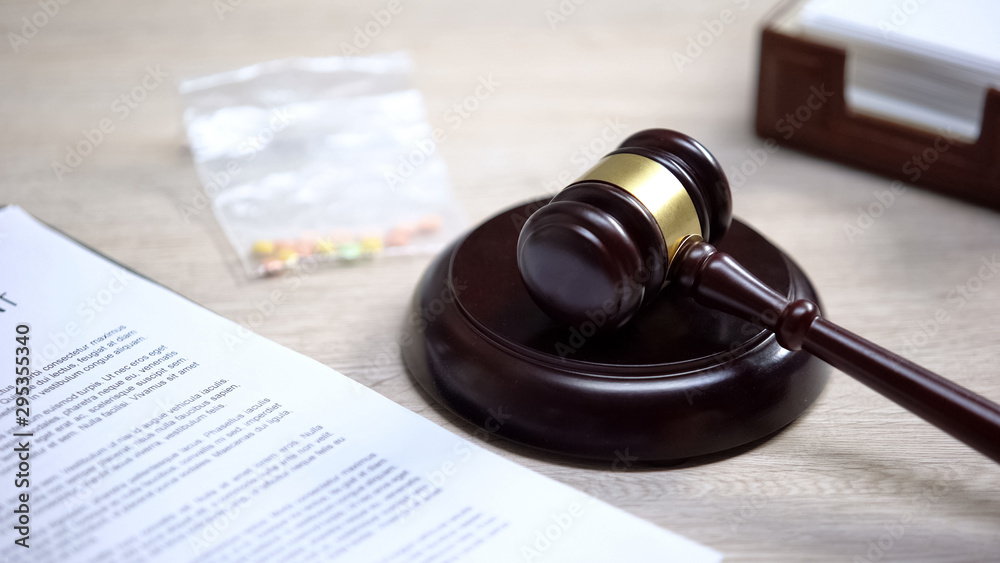 Drug pills on table, gavel lying on sound block, illegal medicine, judgment