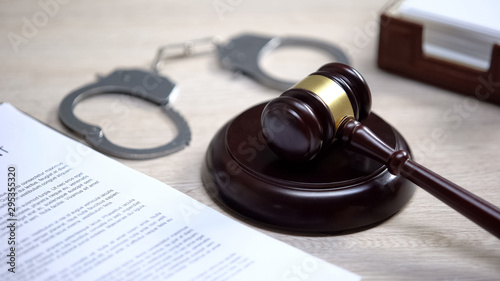 Fotografie, Obraz Handcuffs on table, gavel lying on sound block, crime punishment, law order