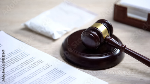 Plastic packet on table, gavel lying on sound block, drug trafficking control