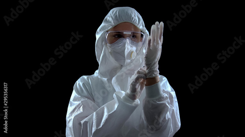 Foto Person in protective suit wearing rubber gloves against dark background, toxins