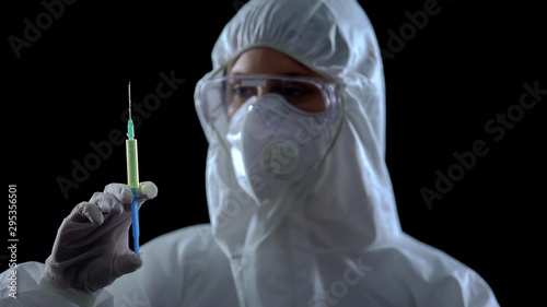 Medical worker showing syringe against dark background, counterfeit medications