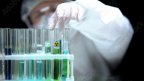 Lab worker taking test tube with green radioactive sample, ecological pollution photo