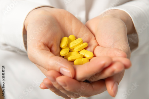 Yellow drig pills in woman doctor hands
