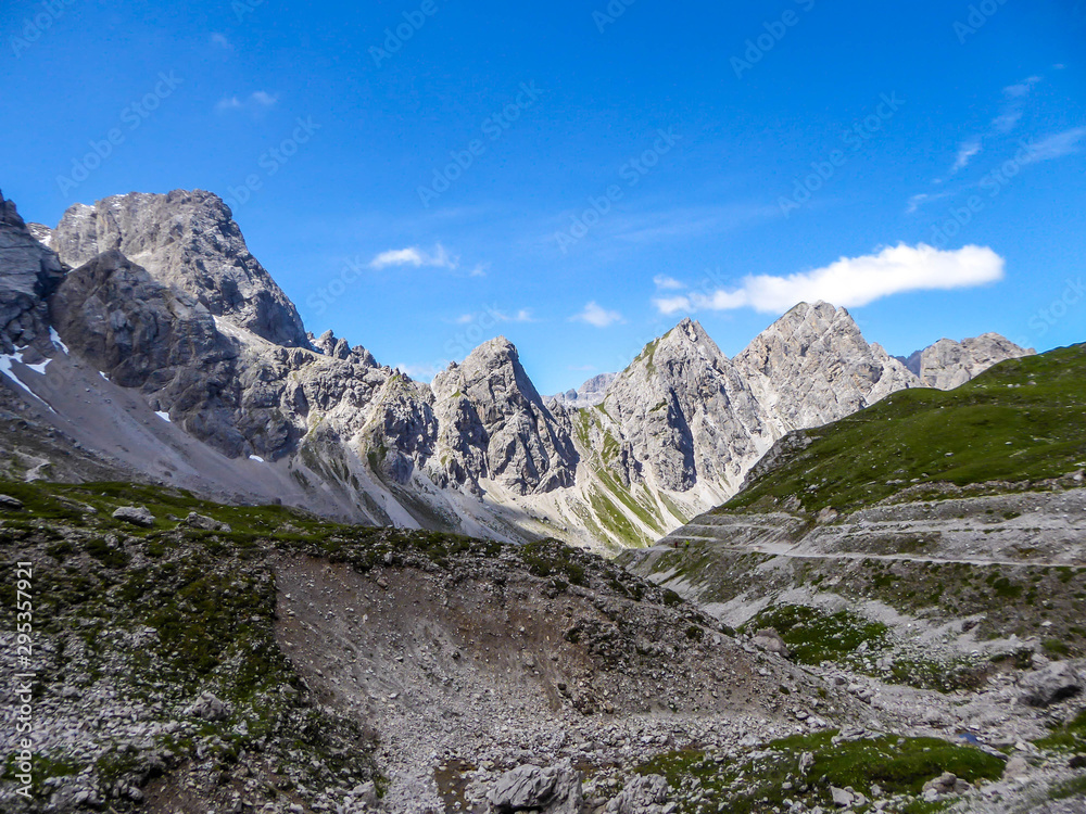 Valley located between sharp and stony mountain range of Lienz Dolomites, Austria. The slopes are barren, with little grass on it. Dangerous mountain climbing. Clear and beautiful day. Natural beauty