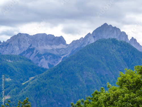 A distanced view on sharp and stony mountain range of Lienz Dolomites, Austria. The slopes are barren, with little grass on it. Dangerous mountain climbing. Clear and beautiful day. Natural beauty