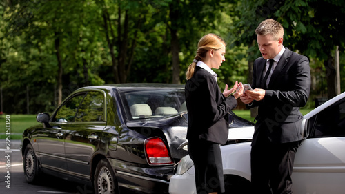 Fotografie Male driver giving dollars woman car accident, traffic collision settlement