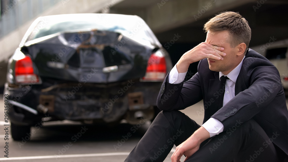 Desperate man sitting asphalt on crashed car background, automobile accident - obrazy, fototapety, plakaty 