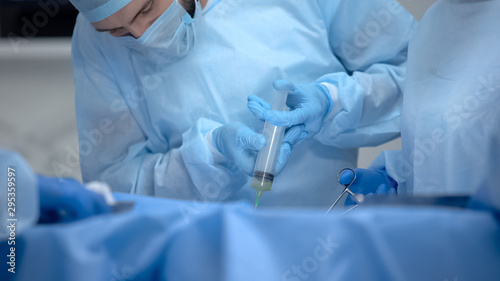 Professional anesthesiologist making injection during hospital operation, health