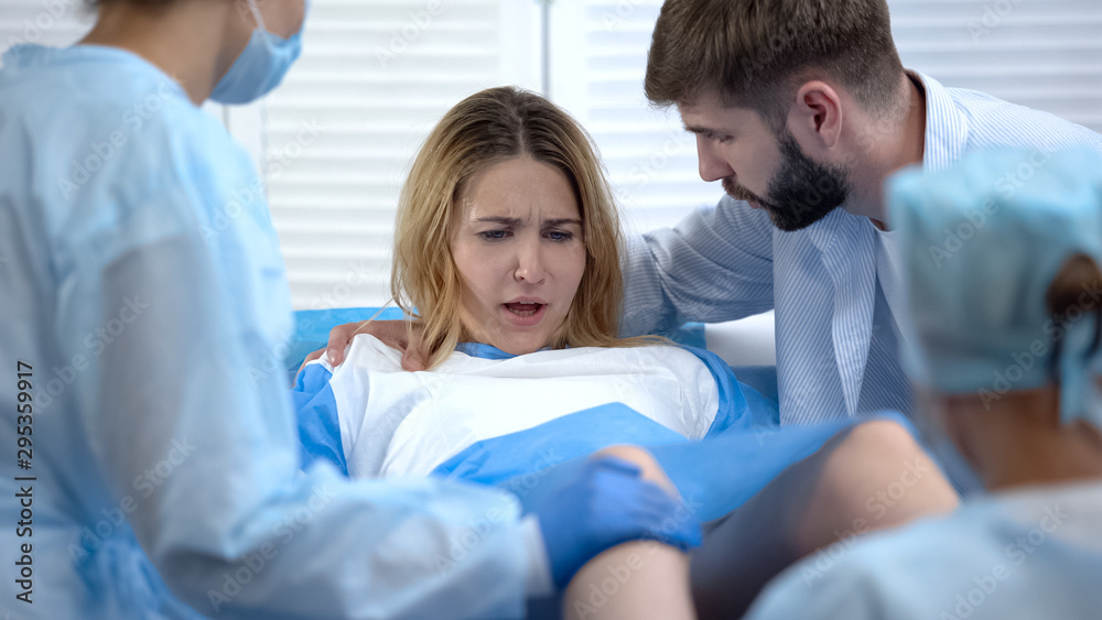 Man supporting wife hardly breathing, pushing to give child birth, hospital Man supporting wife hardly breathing, pushing to give child birth, hospital