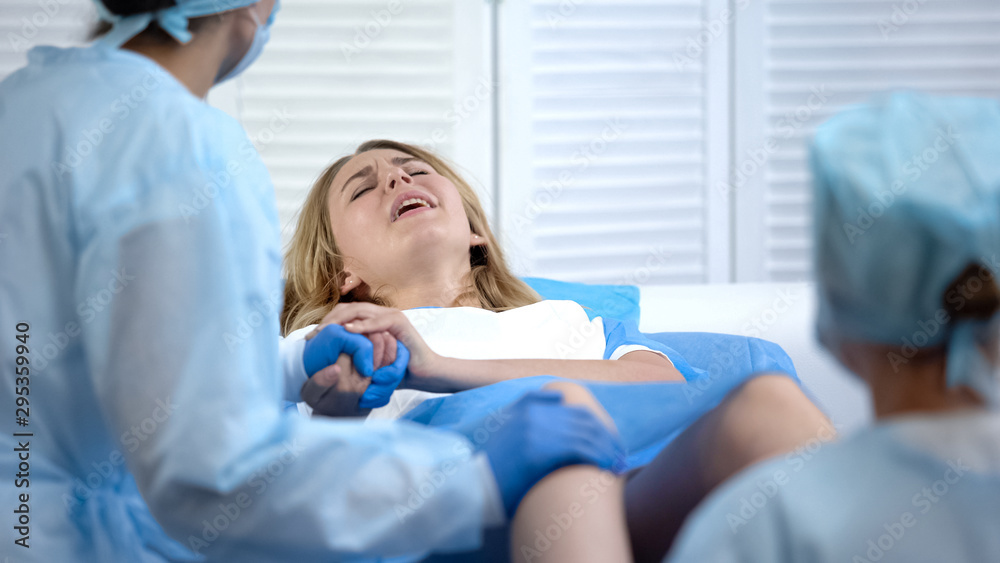 Difficult child birth process, obstetricians supporting female, natural labour Difficult child birth process, obstetricians supporting female, natural labour