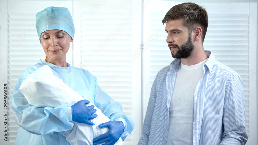 Obraz premium Nurse looking at child before giving baby to father, leaving maternity hospital