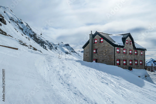 A big alpine cottage covered snow in Mölltaler Gletscher, Austria. Thick snow covers the surroundings. Clear weather. Perfectly groomed slopes. Beautiful and serene mountains covered with snow. © Chris