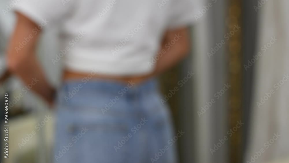Blurred background woman standing in front of the mirror is wearing blue jeans. Blurred background woman standing in front of the mirror is wearing blue jeans.