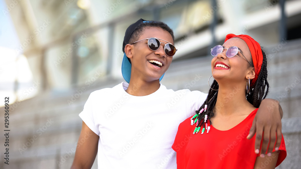 Fototapeta premium Fashionable teenagers in sunglasses hugging and laughing, modern youth, trends
