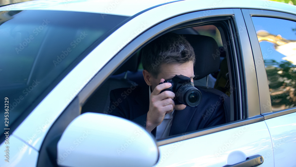 Private detective spying from car, taking photos on camera, investigation Private detective spying from car, taking photos on camera, investigation