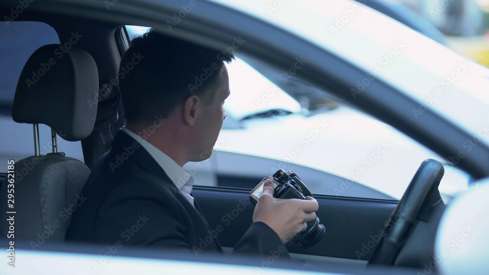 Private agent with camera sitting in car, searching for evidence of cheating Private agent with camera sitting in car, searching for evidence of cheating