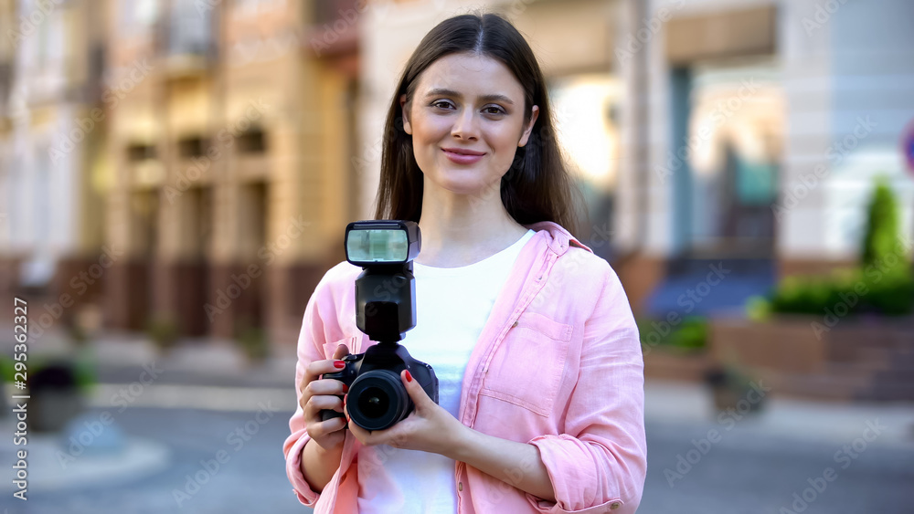Smiling young woman standing with camera on city street, photography lessons Smiling young woman standing with camera on city street, photography lessons