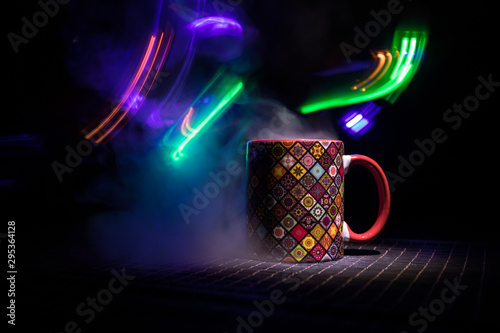 Beautiful eastern style textured ceramic cup of coffee (or tea) with smoke over dark toned background.