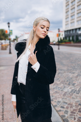 Fashionable beautiful young blondie woman posing in trendy fashionable coat outdoors. Beauty, fashion, modeling concept