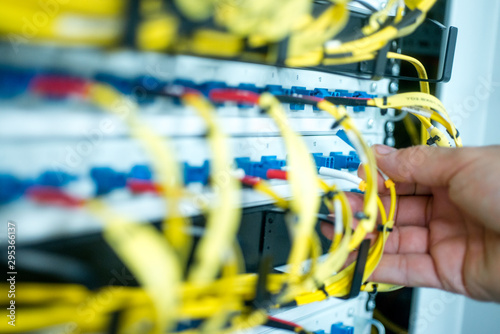 human hand fixing fiber glass cable into control panel