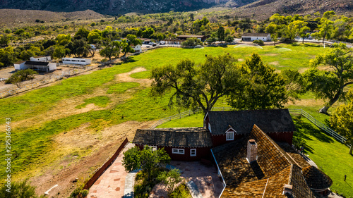 Beautiful view of famous Spring Mountain Ranch State Park near Las Vegas and Red Rock Canyon, Nevada during autumn with pink and red rock mountains, blue sky, green trees and grass, and purple hills