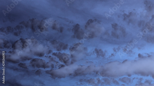 An abstract low key view of dark clouds against a blue sky.