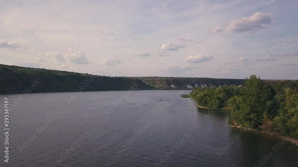 along the riverbank 4K aerial view, Drone flight along the riverbank moving near the trees.