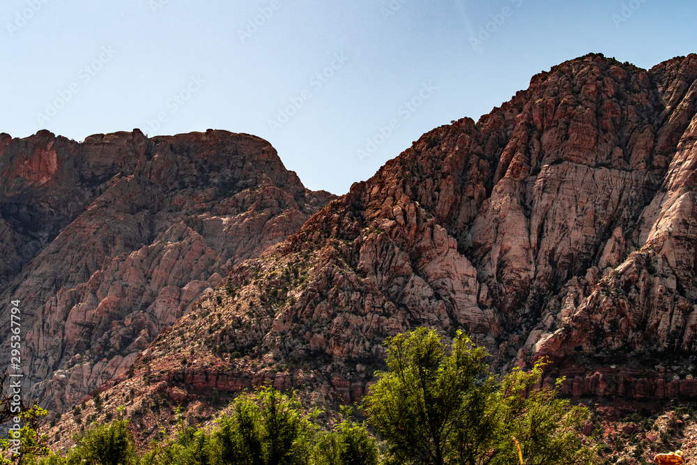 Beautiful view of famous Spring Mountain Ranch State Park near Las Vegas and Red Rock Canyon, Nevada during autumn with pink and red rock mountains, blue sky, green trees and grass, and purple hills