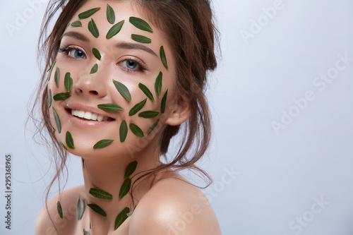 happy girl with green leaves on her body smiling to the camera