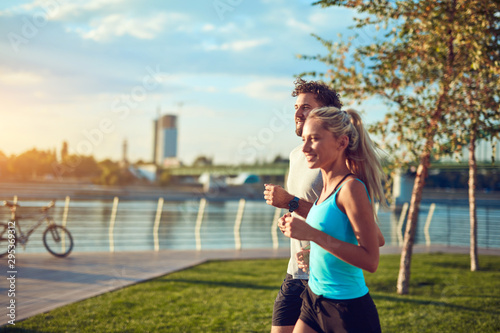 Modern woman and man jogging / exercising in urban surroundings near the river.