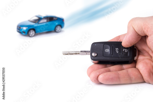 Car key in the hand. Blue car in the background