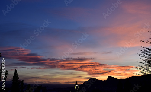 beautiful sunset with the moon high and the silhouette of mountains in the background