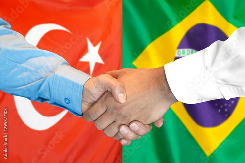Handshake on Turkey and Brazil flag background.