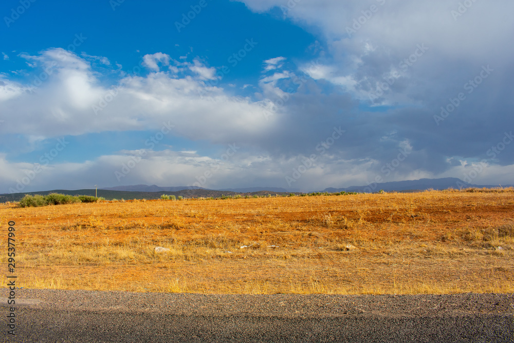 Road to Atlas Mountains in Morocco. yellow and brown grassy fields against blue sky 