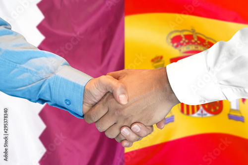 Handshake on Qatar and Spain flag background.
