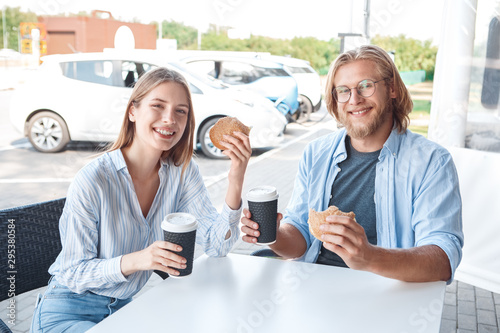 Young adult friends eating food and drinking coffee on parking