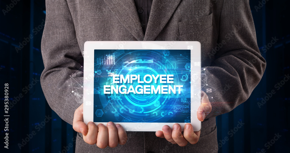 Young business person working on tablet and shows the inscription: EMPLOYEE ENGAGEMENT, business concept Young business person working on tablet and shows the inscription: EMPLOYEE ENGAGEMENT, business concept