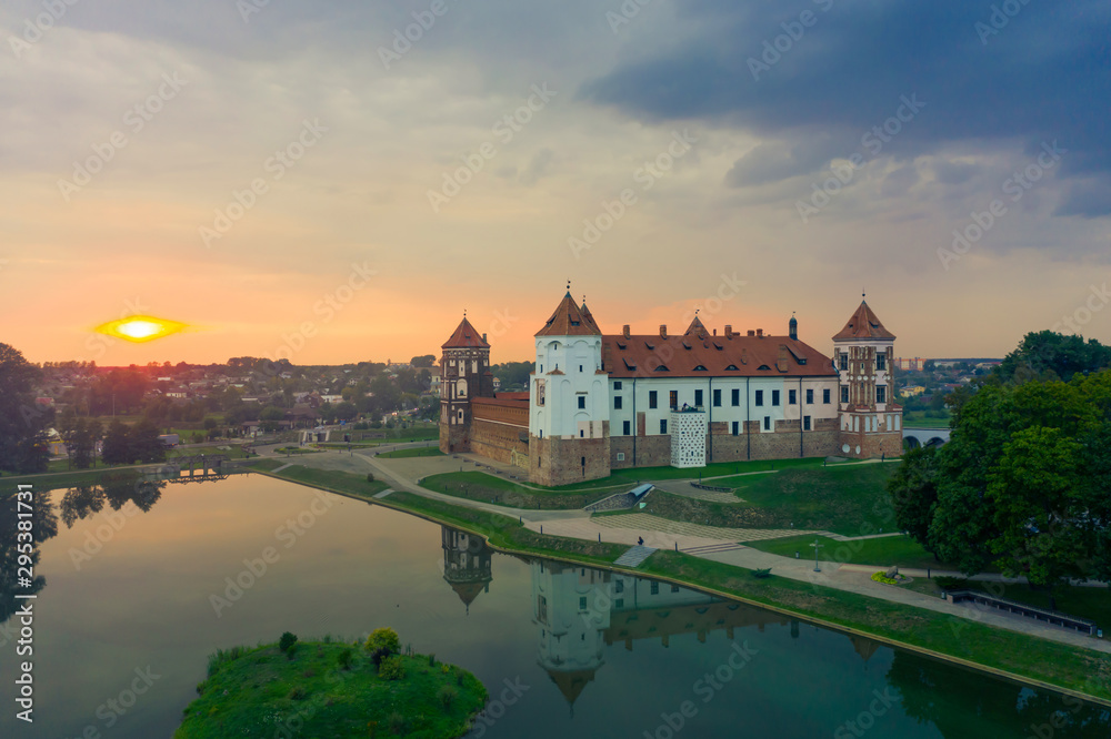 Mirsky Castle and its reflection in the lake in summer. Sunset in cloudy weather with rain clouds. Mirsky Castle and its reflection in the lake in summer. Sunset in cloudy weather with rain clouds.