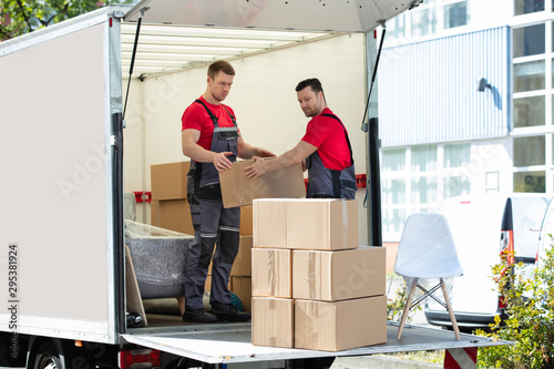 Young Men Stacking The Cardboard Boxes In Moving Truck photo