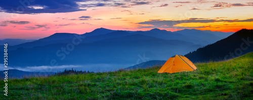 Orange tent in the mountains at sunset