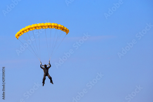 Skydiver with yellow parachute in blue sky