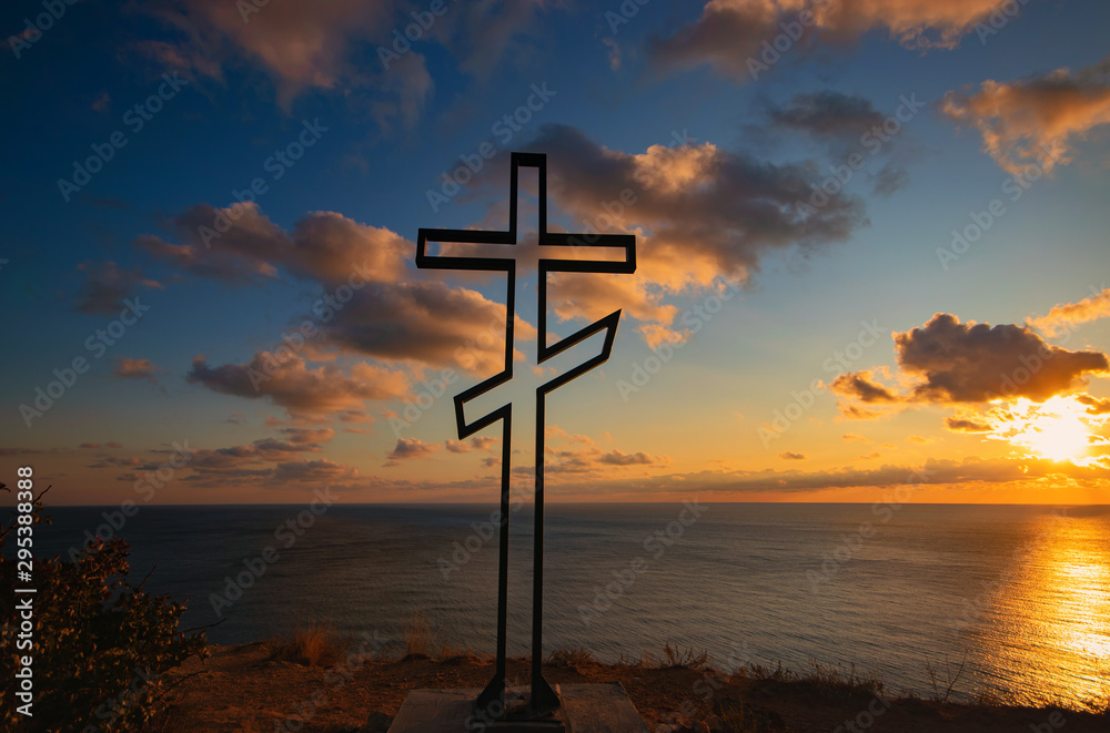 Christian cross on the background of the sea and sunset