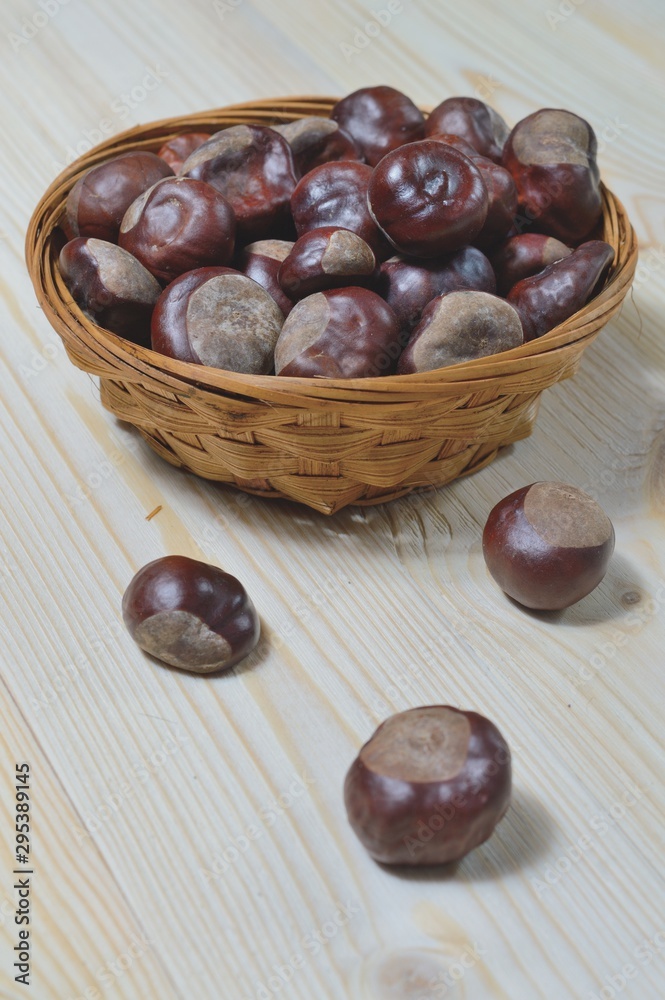 Obraz premium chestnuts in wicker cup on wooden background
