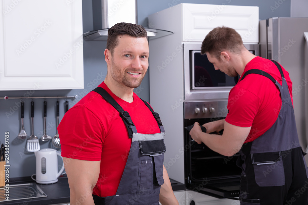 Male Technician With His Assistant Repairing The Oven Male Technician With His Assistant Repairing The Oven