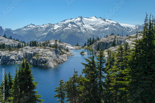 Robin Lake surrounded by granite and trees with snow-capped Mt. Daniel towering in the background under a clear sky in the Alpine Lakes Wilderness, Washington State, USA. photo